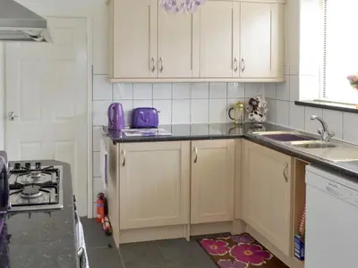 a kitchen with white cabinets and purple appliances at Rossall Beach Cottage in Cleveleys