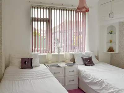 two beds sitting next to a window in a bedroom at Rossall Beach Cottage in Cleveleys