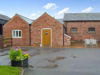 a brick house with a yellow door and a patio at The Stable in Burscough