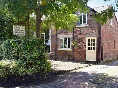 a brick building with a white door and a tree at The Stable in Burscough