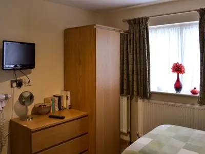 a bedroom with a bed and a dresser with a television at The Stable in Burscough
