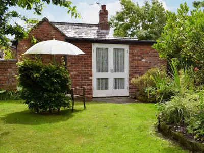 a brick house with a white door and an umbrella at The Dairy in Burscough