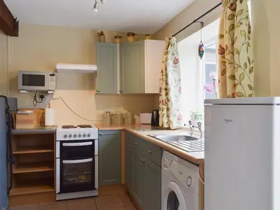 a kitchen with green cabinets and a sink and a dishwasher at The Shippon in Burscough