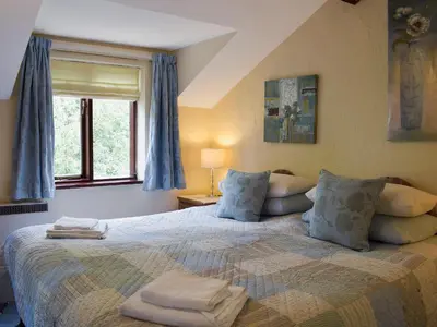 a bedroom with a large bed with blue curtains at The Shippon in Burscough