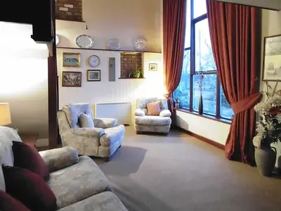 a living room with a couch and chairs and a window at The Granary in Burscough