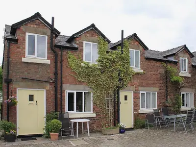 a brick house with tables and chairs in front of it at The Granary in Burscough