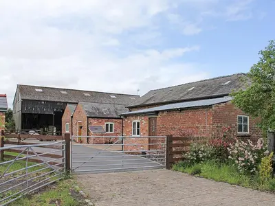 a brick barn with a gate in front of it at The Granary in Burscough