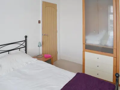a bedroom with a white bed and a wooden cabinet at Sandfield The Promenade in Southport