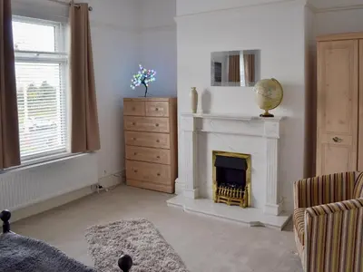 a living room with a fireplace and a dresser at Sandfield The Promenade in Southport