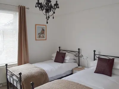 a bedroom with two beds and a chandelier at Sandfield The Promenade in Southport