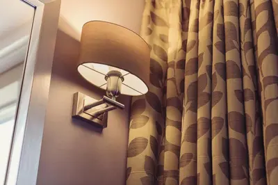 a lamp on a wall next to a curtain at Abbey House Hotel in Barrow in Furness