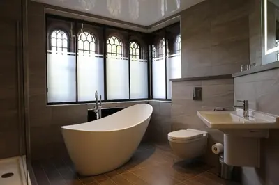 a bathroom with a tub and a toilet and a sink at Abbey House Hotel in Barrow in Furness