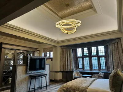 a bedroom with a bed and a chandelier and a television at Abbey House Hotel in Barrow in Furness