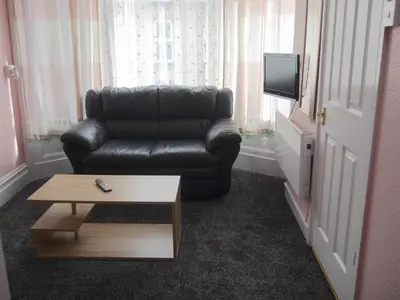 a living room with a black leather couch and a coffee table at Blackpool Beach Holiday Flats in Blackpool