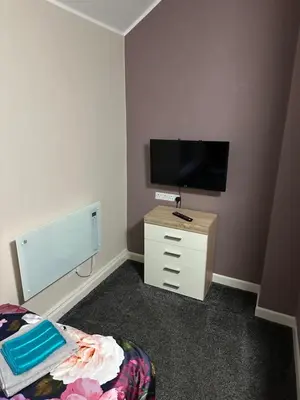 a bedroom with a television and a dresser with a bed at Blackpool Beach Holiday Flats in Blackpool