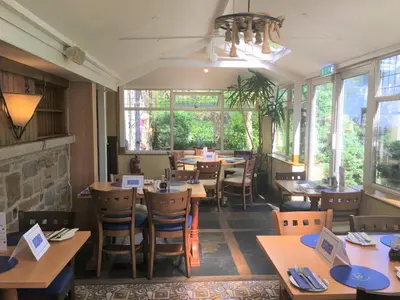 a restaurant with wooden tables and chairs and windows at Calf's Head Hotel in Clitheroe