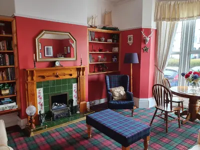 a living room with a fireplace and a table and a mirror at The Braemar Southport in Southport