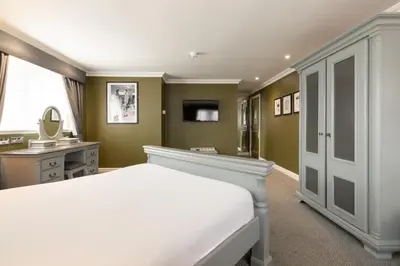 a bedroom with a bed and a vanity and a mirror at The Sir Thomas Hotel in Liverpool