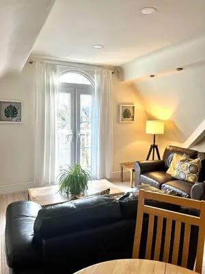 a living room with a black leather couch and a table at Holland House in New Brighton