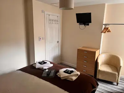 a bedroom with a bed and a chair and a television at The Oxfordshire in Blackpool
