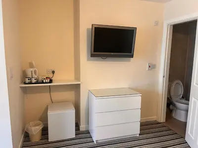 a bathroom with a toilet and a tv on the wall at The Oxfordshire in Blackpool