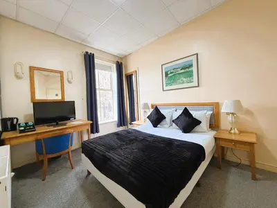 a bedroom with a bed and a desk and a television at Throstles Nest Hotel in Liverpool