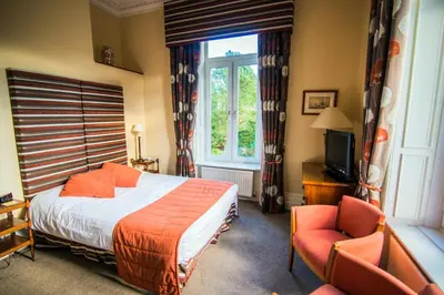 a bedroom with a bed and a window and two chairs at Astley Bank Hotel in Darwen