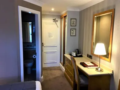 a room with a desk and a bed and a bathroom at Astley Bank Hotel in Darwen