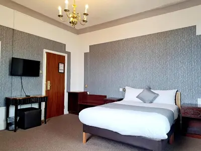 a bedroom with a bed and a desk and a television at Scarisbrick Hotel in Southport