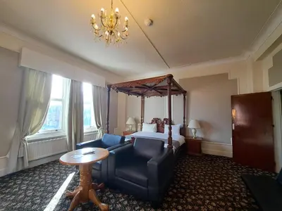 a hotel room with a bed and a chair and a table at Scarisbrick Hotel in Southport