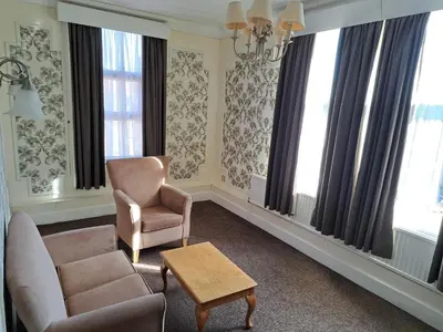 a living room with a couch and chairs and windows at Scarisbrick Hotel in Southport
