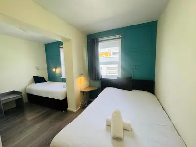 a small room with two beds and a window at Calypso hotel Blackpool in Blackpool