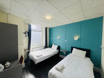 a room with two beds and a blue wall at Calypso hotel Blackpool in Blackpool