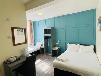 a bedroom with a large bed with a blue headboard at Calypso hotel Blackpool in Blackpool
