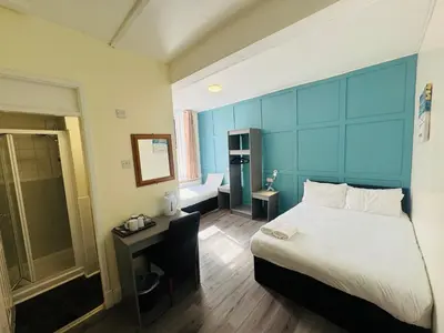 a bedroom with a large bed with a blue headboard at Calypso hotel Blackpool in Blackpool