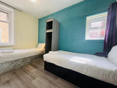 two beds in a room with blue walls and windows at Calypso hotel Blackpool in Blackpool