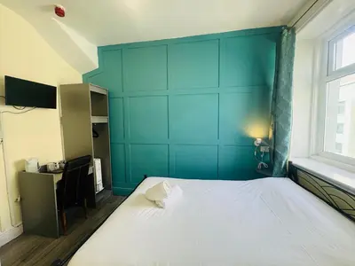 a bedroom with a large bed with a blue wall at Calypso hotel Blackpool in Blackpool