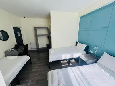 a room with two beds and a desk in it at Calypso hotel Blackpool in Blackpool