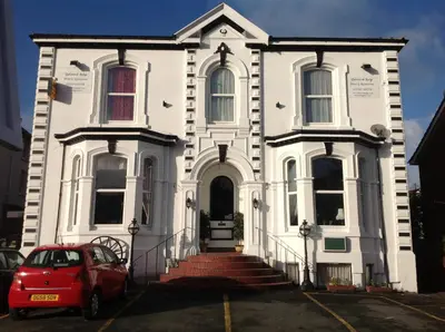 a white house with a red car parked in front of it at Balmoral Lodge Hotel in Southport