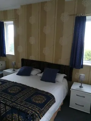 a bedroom with two beds with blue pillows at Balmoral Lodge Hotel in Southport