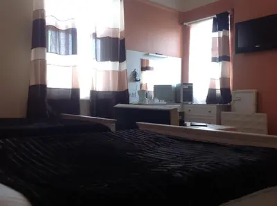 a bedroom with a bed and a large window at Balmoral Lodge Hotel in Southport