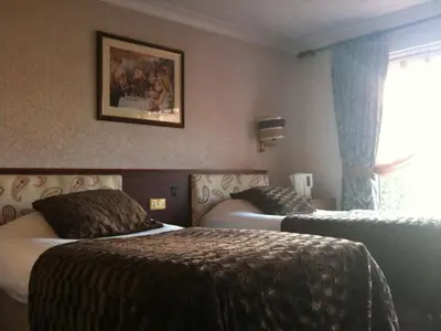 a hotel room with two beds and a window at Balmoral Lodge Hotel in Southport