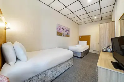 a room with two beds and a flat screen tv at Bluewaters Hotel, Blackpool North Promenade in Blackpool