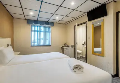 a bedroom with two white beds and a bathroom at Bluewaters Hotel, Blackpool North Promenade in Blackpool