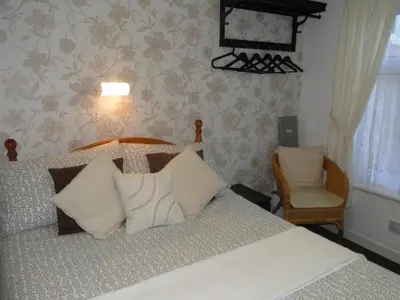 a bedroom with a bed with white pillows and a chair at Windsor Hotel in Blackpool