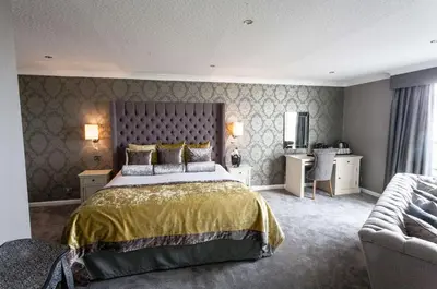 a large bedroom with a bed and a couch at The Glendower Hotel in Lytham St Annes
