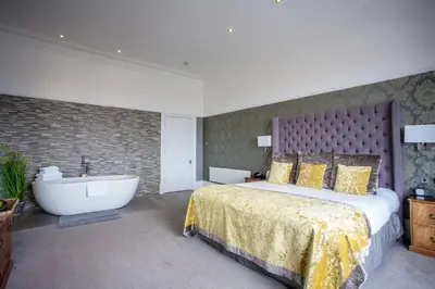 a bedroom with a large bed and a bath tub at The Glendower Hotel in Lytham St Annes