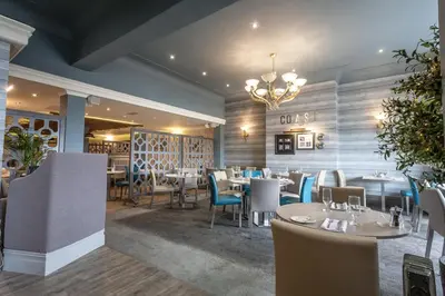 a restaurant with tables and chairs and a chandelier at The Glendower Hotel in Lytham St Annes