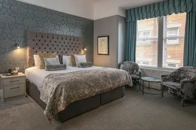 a bedroom with a large bed and a chair at The Glendower Hotel in Lytham St Annes