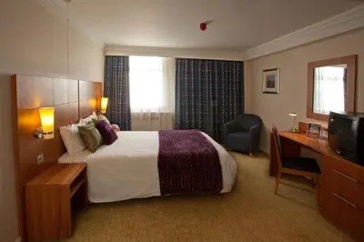 a hotel room with a bed and a desk and a television at Britannia Hotel Bolton in Bolton